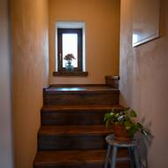 Dům je dvoupodlažní, do patra vede dřevěné schodiště